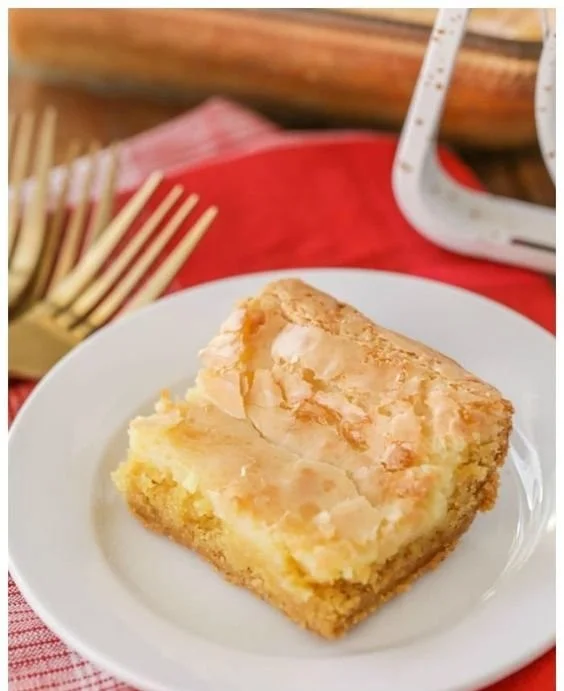 Delicious slice of Gooey Butter Cake topped with powdered sugar on a plate