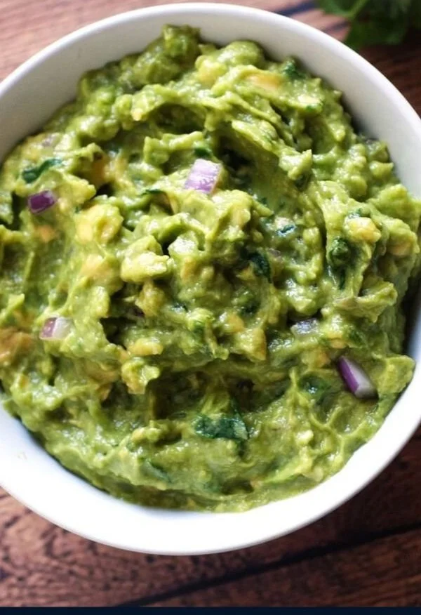 A bowl of guacamole with chipotle served with tortilla chips.
